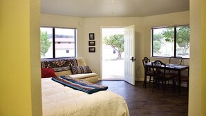 A bedroom with a bed, a chair, a dining table, and a ceiling fan. - Authentic Native American Hogan Experience near Chaco Cultural Historical Park (Counselor)