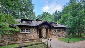 Un bâtiment en pierre avec une porte en bois, portant l’inscription « Salle de bain », et une rampe d’accès pour les personnes à mobilité réduite menant à l’entrée.