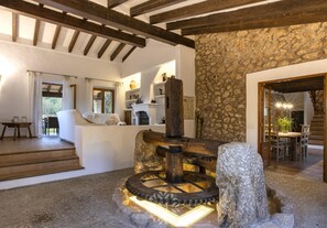Un interior rústico con vigas de madera a la vista, pared de piedra y una fuente de agua de piedra.