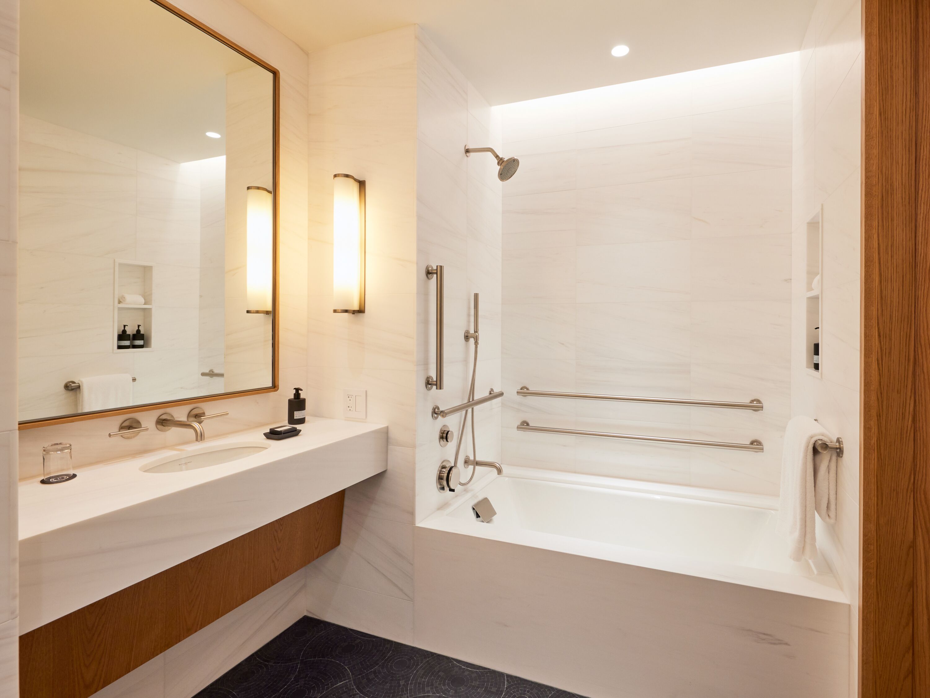 A modern bathroom with a large mirror, a vanity with a sink, a bathtub, and a shower area.