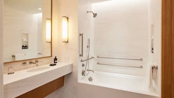 A modern bathroom with a large mirror, a vanity with a sink, a bathtub, and a shower area.
