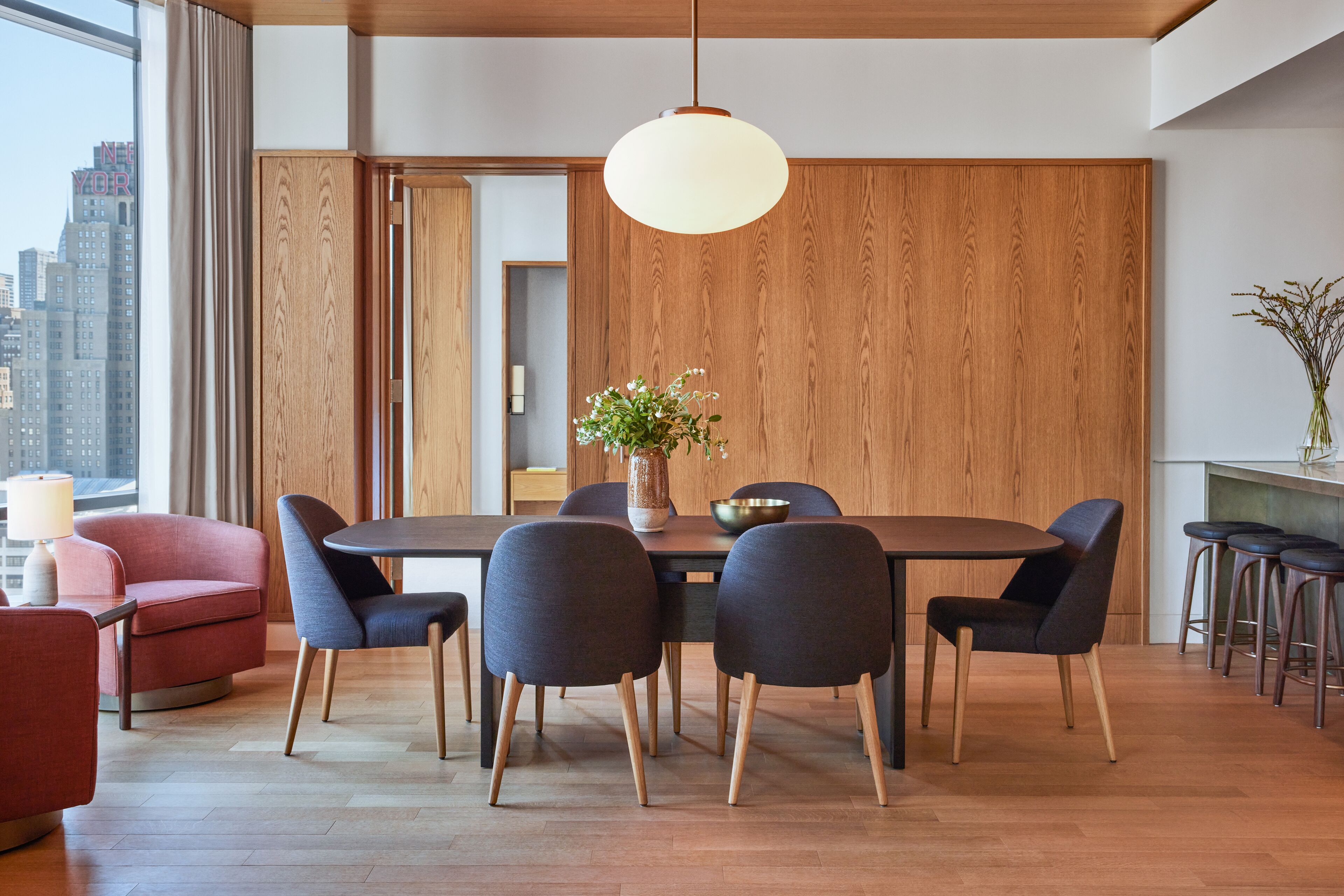 A modern dining area with a wooden wall, a round table, and six chairs.