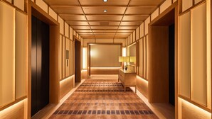 A hallway with wooden paneling, a checkered carpet, and a mirror on the right wall.