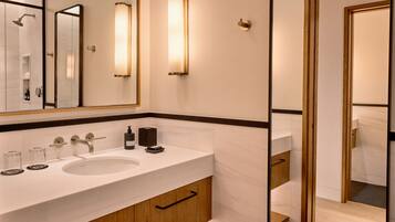 Une salle de bain moderne avec un grand miroir, deux lavabos et une douche.