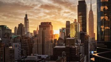 A cityscape with high-rise buildings, including the Empire State Building, during sunset.