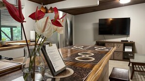 A modern kitchen with a wooden countertop, a coffee machine, and a vase with flowers.