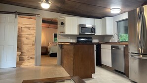 A modern kitchen with white cabinets, stainless steel appliances, and a wooden island.