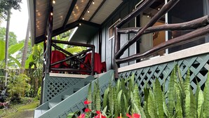 A wooden staircase leading to a covered porch with a lattice wall and red chairs.