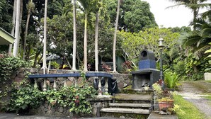 A stone staircase leading to a tiled bench area, surrounded by lush greenery and a stone wall.