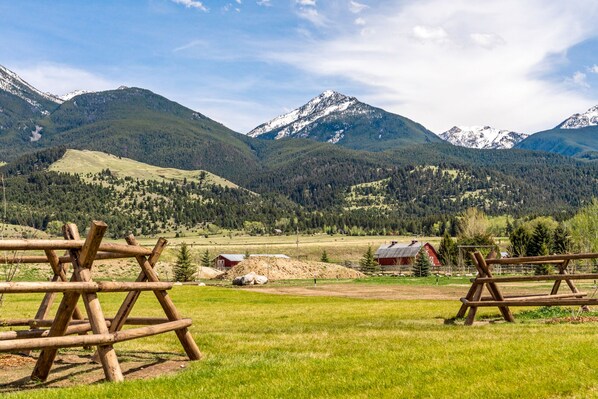 A rural landscape with mountains, a grassy field, and wooden fences. - Beautiful Log Cabin Near Yellowstone Park (Livingston)
