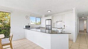 A modern kitchen with a central island, a microwave, a refrigerator, and a sink.