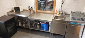 Cocina comercial equipada con electrodomésticos de acero inoxidable, como horno, microondas y lavavajillas.