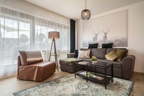 Un salon moderne avec un canapé, une table basse, un lampadaire et une grande fenêtre.
