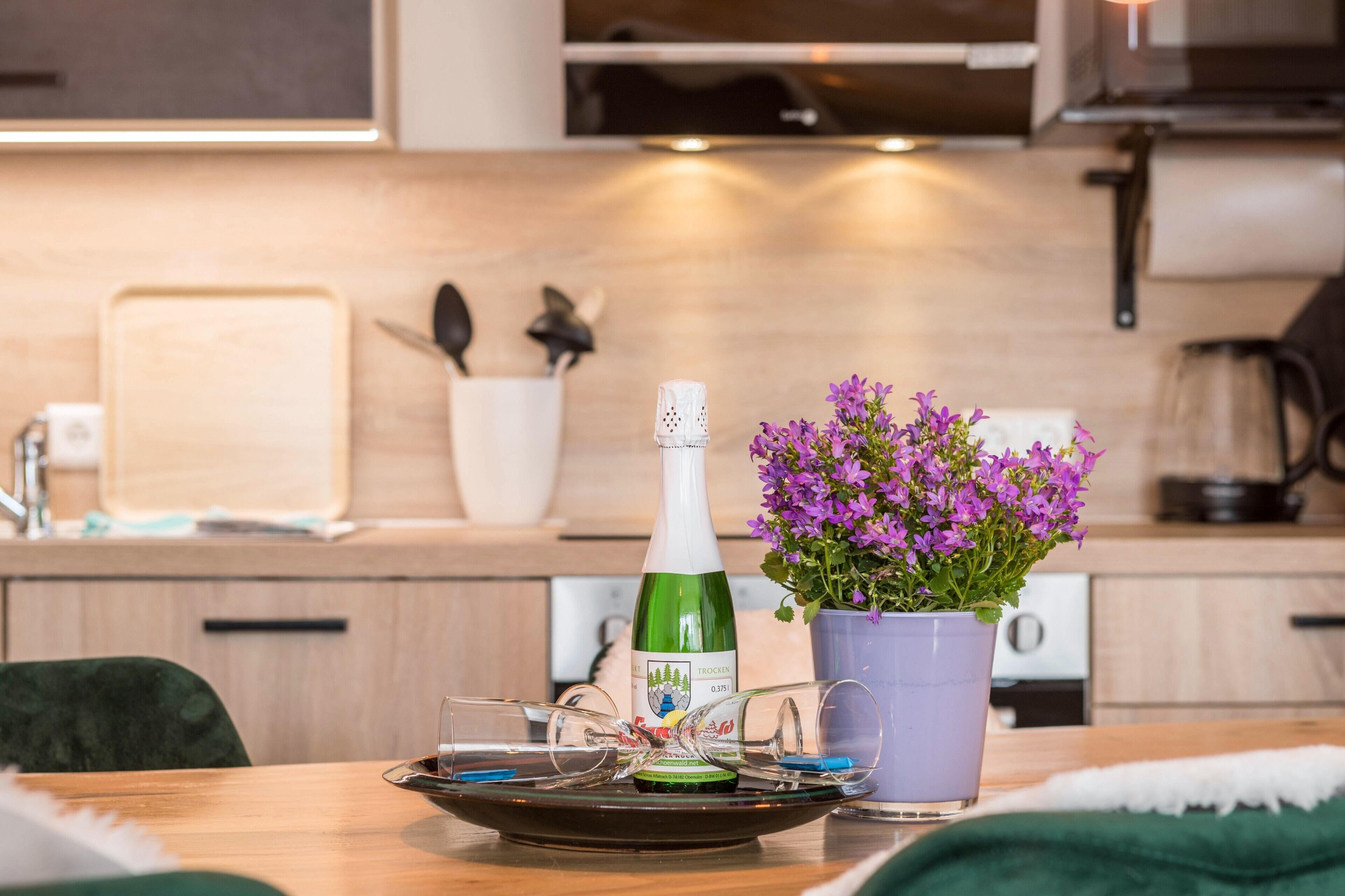 A kitchen with a bottle of wine, glasses, and a potted plant.