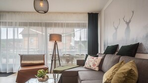 Ett vardagsrum med en soffa, ett soffbord, en lampa och en vägg dekorerad med silhuetter av rådjur.