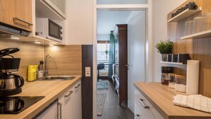 A modern kitchen with a microwave, coffee maker, and shelves with jars.