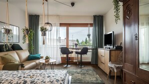A bedroom with a bed, a desk, two chairs, a TV, and a wardrobe.