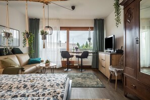 A bedroom with a bed, a desk, two chairs, a TV, and a wardrobe.