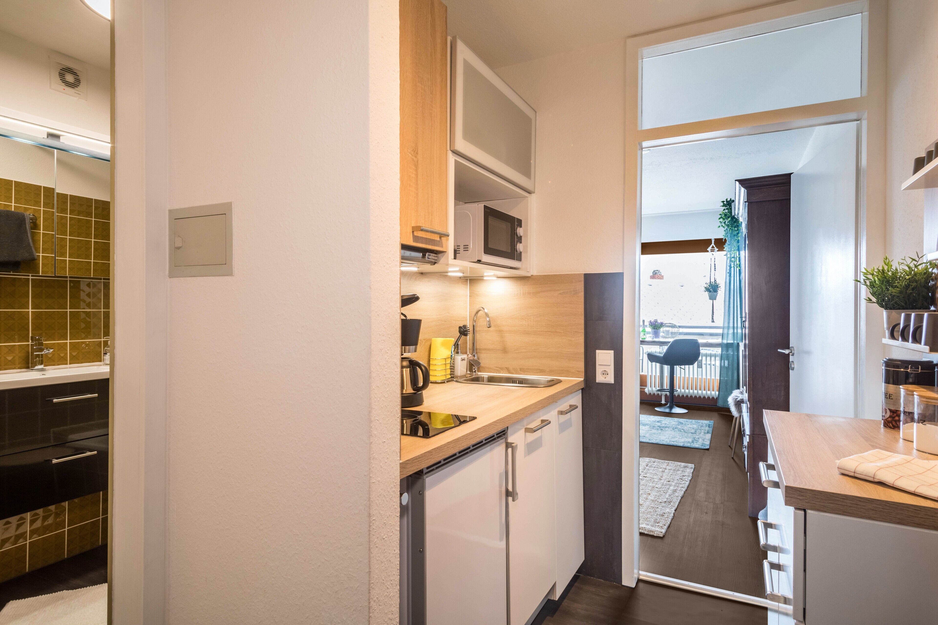 Une cuisine compacte équipée d’un four à micro-ondes, d’un évier et d’un plan de travail en bois.