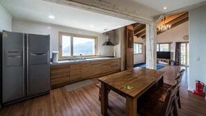 Una cucina moderna con mobili in legno, un frigorifero grande e un'area pranzo con tavolo e sedie in legno.