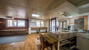Una cucina compatta con isola in legno, forno integrato e finestra con tende.