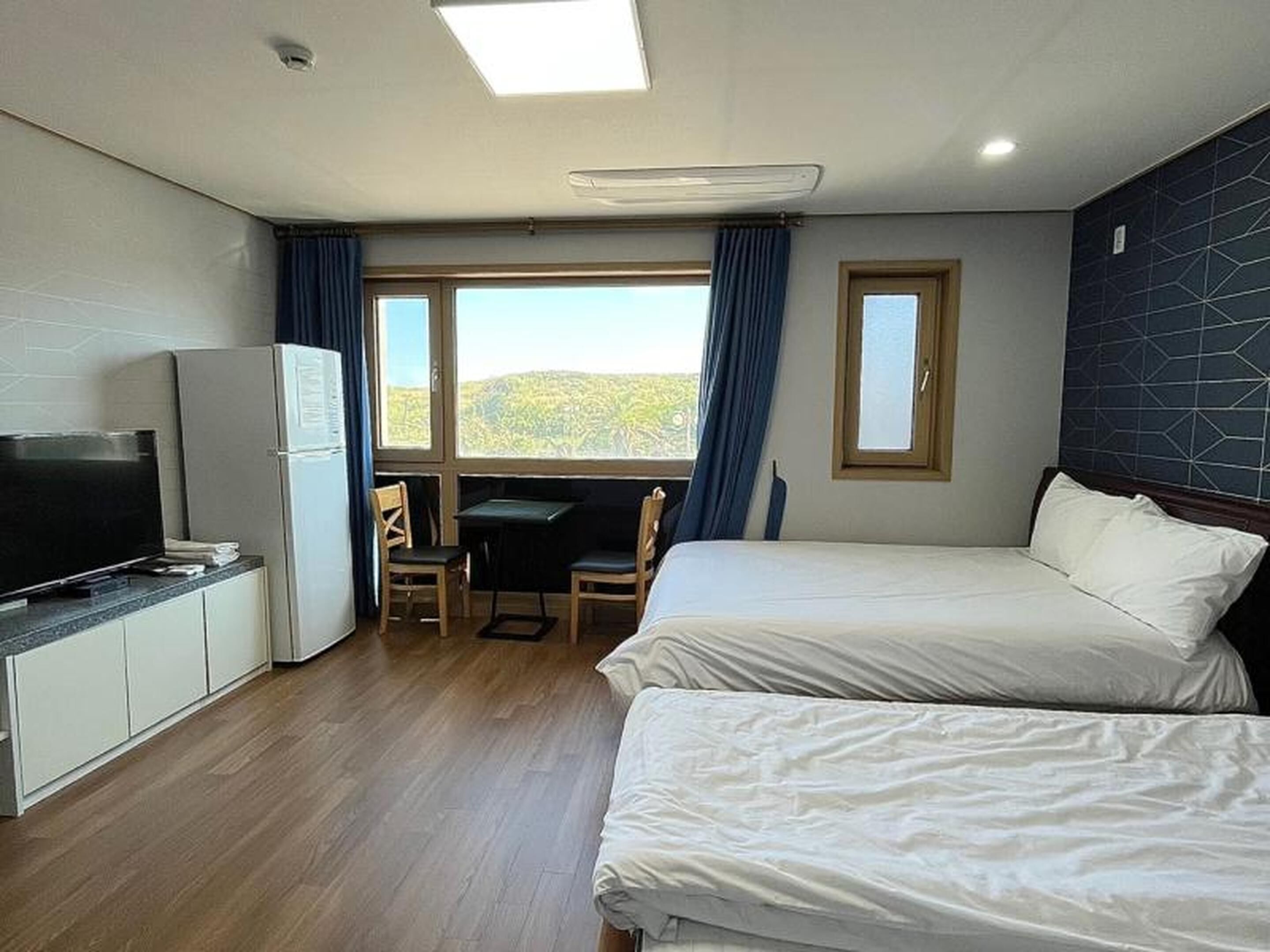 Habitació d'hotel amb dos llits, un escriptori, una televisió i un frigorífic.