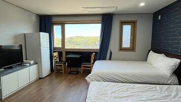 Habitació d'hotel amb dos llits, un escriptori, una televisió i un frigorífic.