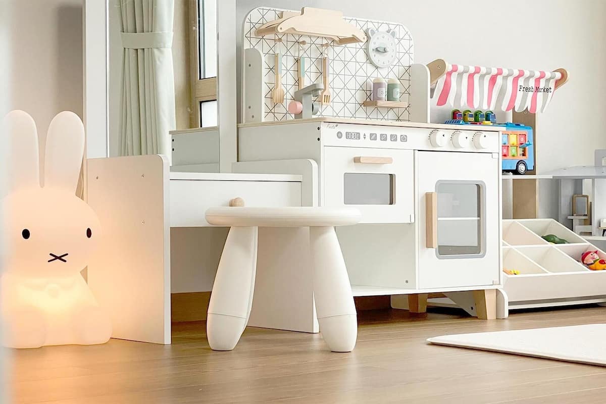 Ein Kinderspielbereich mit einer weißen Spielküche, einem kleinen Tisch und einem Spielzeugauto.