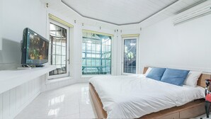 A bedroom with a bed, a TV, and large windows. - Gapyeong Benest Group Pension (Gapyeong)