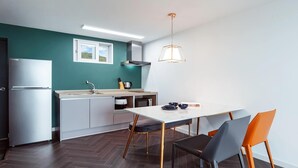 Eine moderne Küche mit weißem Arbeitsplatz, einem Edelstahl-Kühlschrank und einem Essbereich mit weißem Tisch und zwei Stühlen.