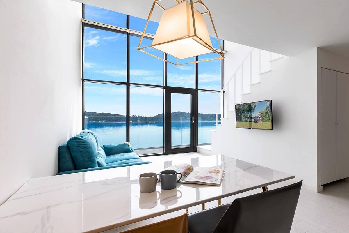 Una habitación moderna con un ventanal que ofrece vistas a un lago y colinas.
