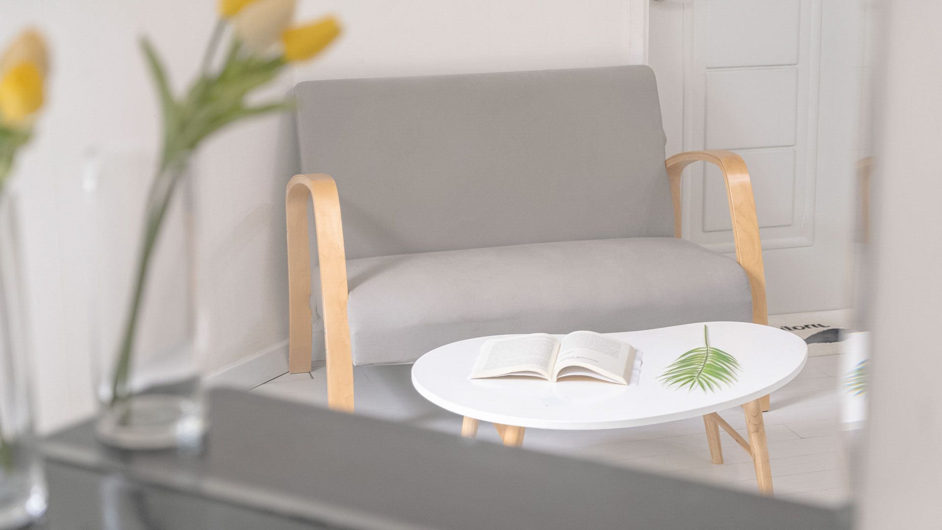 Une pièce moderne avec un canapé gris, une table ronde blanche et un livre.