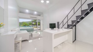 A modern living room with a white sofa, a coffee table, and a TV. There is a staircase with a glass railing leading to an outdoor area with a pool. - Gapyeong Shiny Pension (Gapyeong)