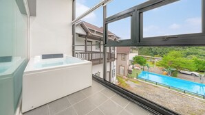 A modern bathroom with a bathtub, large windows, and a view of a swimming pool and neighboring houses. - Gapyeong Shiny Pension (Gapyeong)