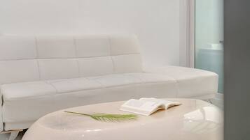Ein modernes, minimalistisches Zimmer mit einem weißen Sofa und einem kleinen, runden Tisch.