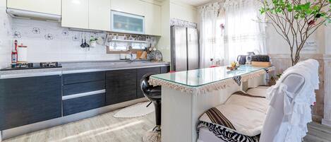 A modern kitchen with a central island, dark cabinetry, and a view of a dining area with a white chair.