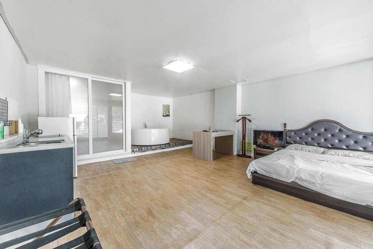 Un dormitorio moderno con cama, escritorio y un amplio ventanal.
