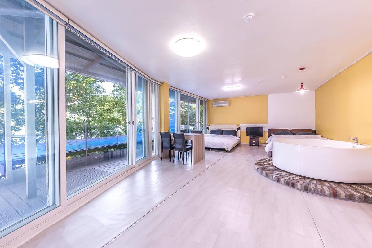 Un dormitorio moderno con una cama grande, una sala de estar separada y un baño con bañera.