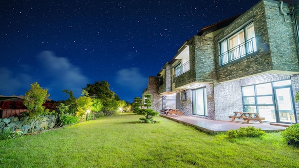 A two-story house with a well-maintained lawn and outdoor seating area.