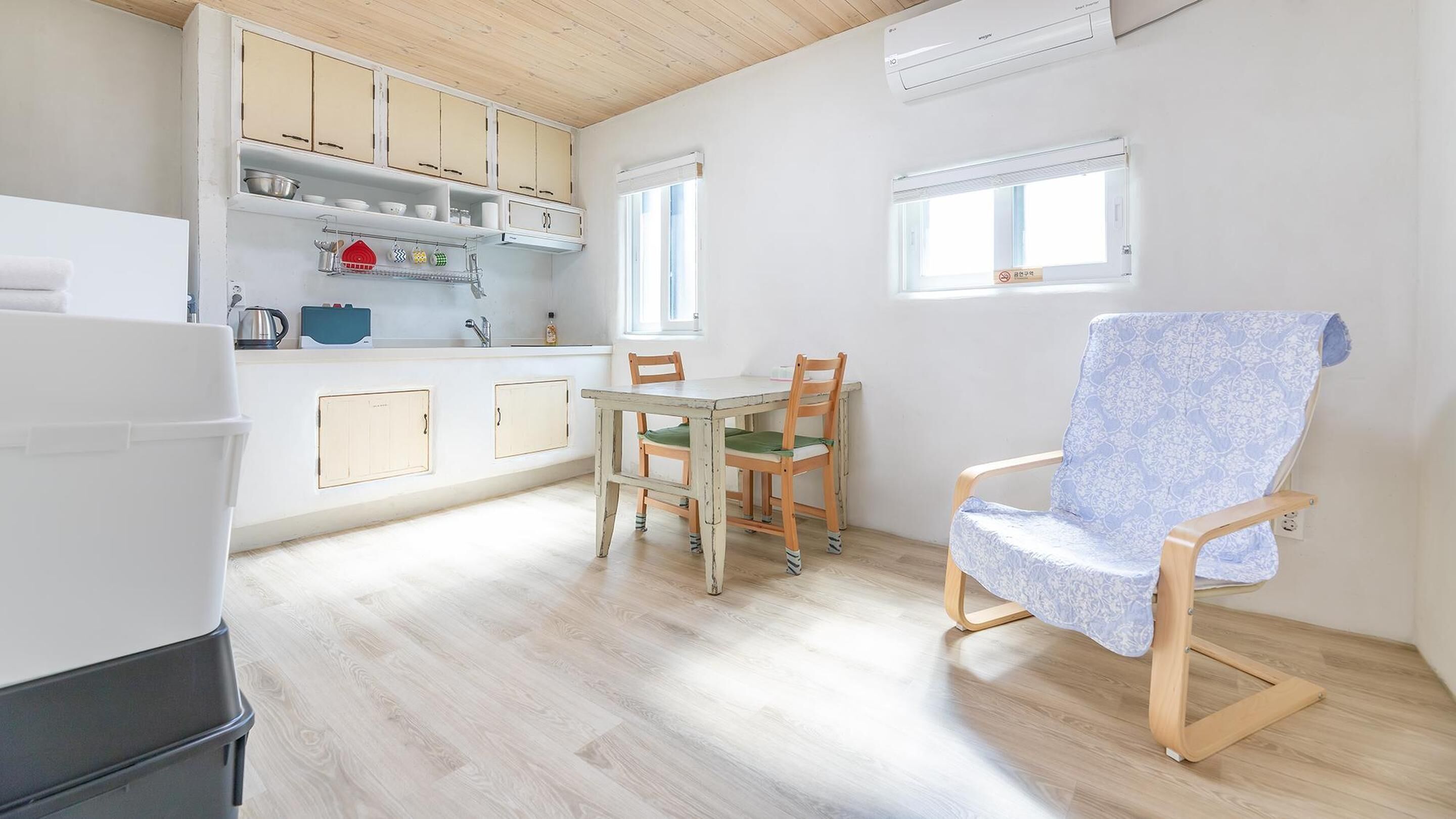 A compact kitchen with wooden cabinets, a dining table with chairs, and a single window.