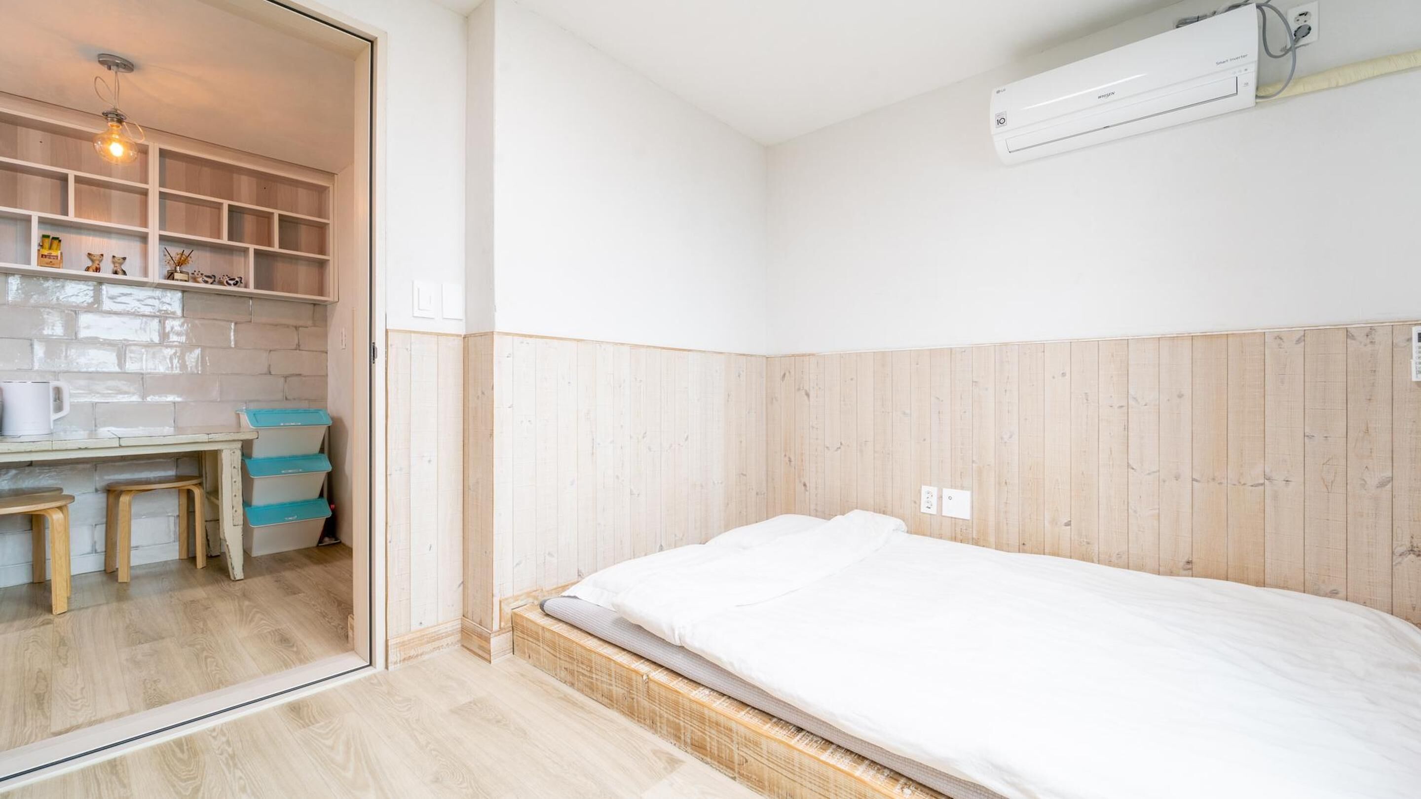 Een slaapkamer met een bed, een bureau met stoel, en een klein kitchenette.