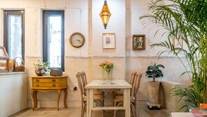 Un coin repas accueillant avec une table et des chaises en bois, une horloge ancienne et un luminaire suspendu.