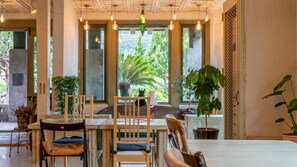 Un espacio interior acogedor con mobiliario de madera, ventanas amplias y lámparas colgantes.
