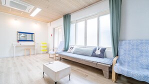 Une pièce lumineuse avec un plancher en bois, un bureau blanc, un banc avec des coussins et une fen être avec des rideaux.