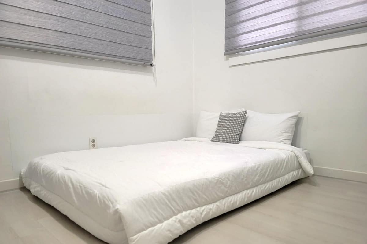 A single bed with white bedding in a room with light-colored walls and flooring.
