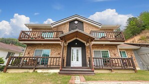 A two-story house with a front porch, a central entrance, and a balcony on each floor. - Gapyeong Peulrei38 Pension (Gapyeong)