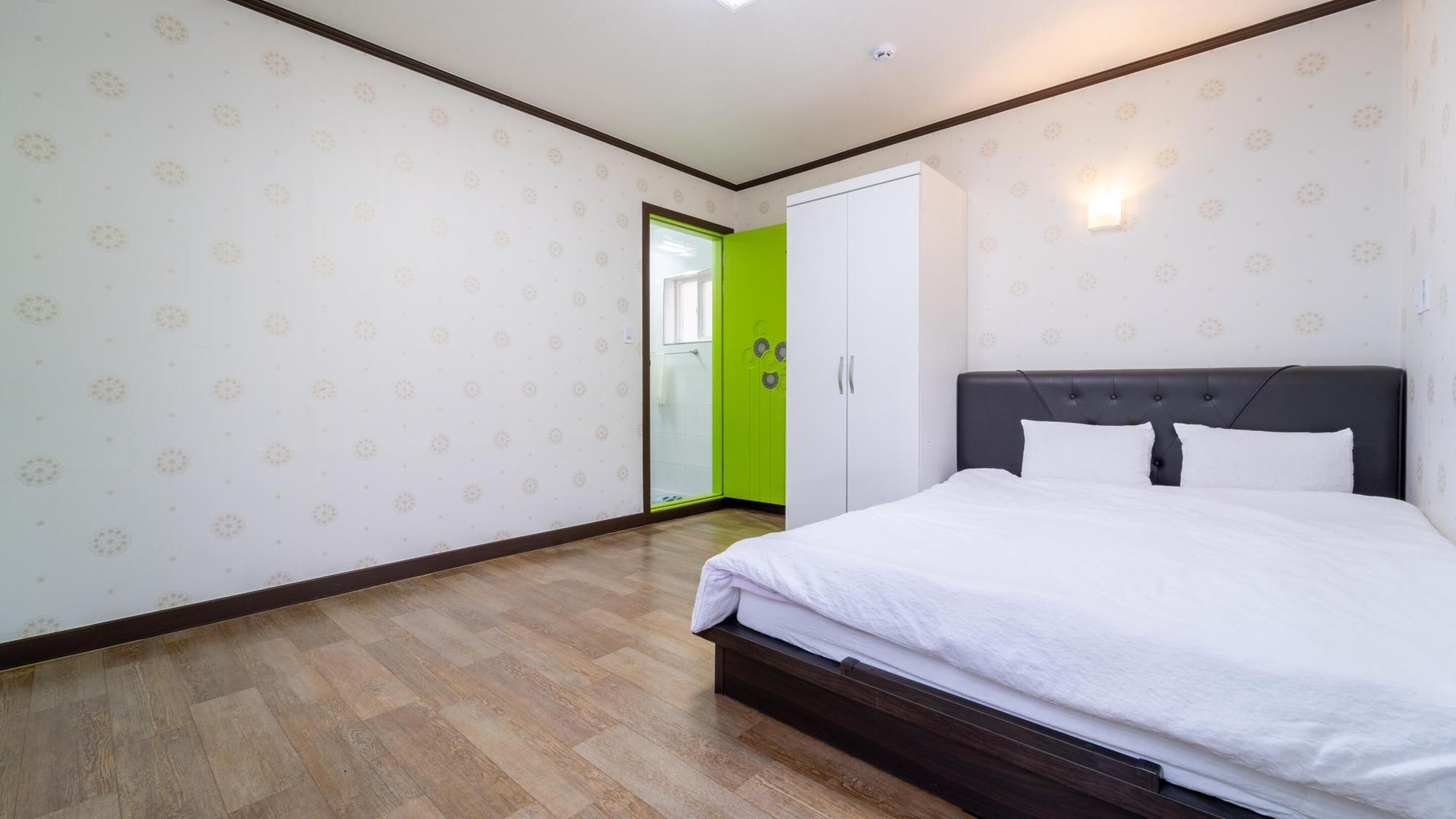 A bedroom with a bed, a wardrobe, and a green door.