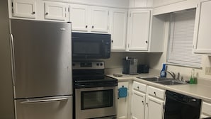 A kitchen with white cabinets, a stainless steel refrigerator, a microwave, an oven, a dishwasher, and a coffee maker. - Canal Run Condo on Intracoastal Waterway (Gulf Shores)