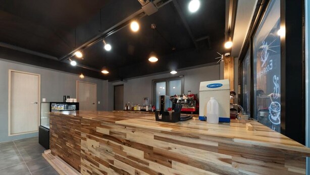 A modern reception area with a wooden reception desk, a coffee machine, and a large window with artwork. - Busan Haeoream Pension (Busan)