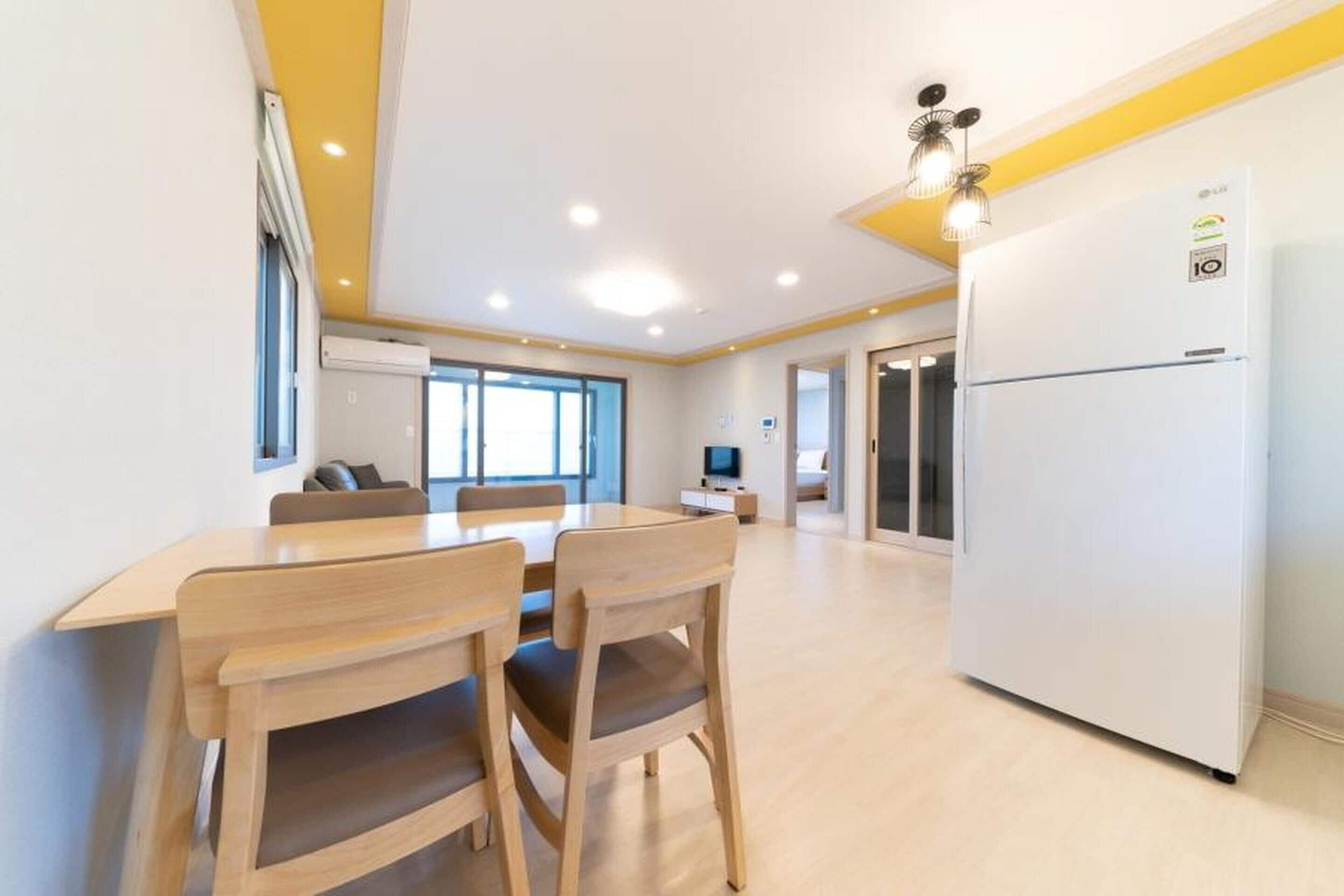 A modern kitchen with a white refrigerator, wooden chairs, and a dining table.